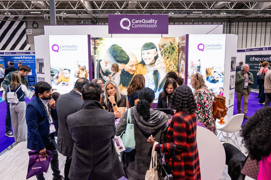 Visitors and professionals gather at the Care Quality Commission stand at Naidex, discussing services and information on a busy exhibition floor.