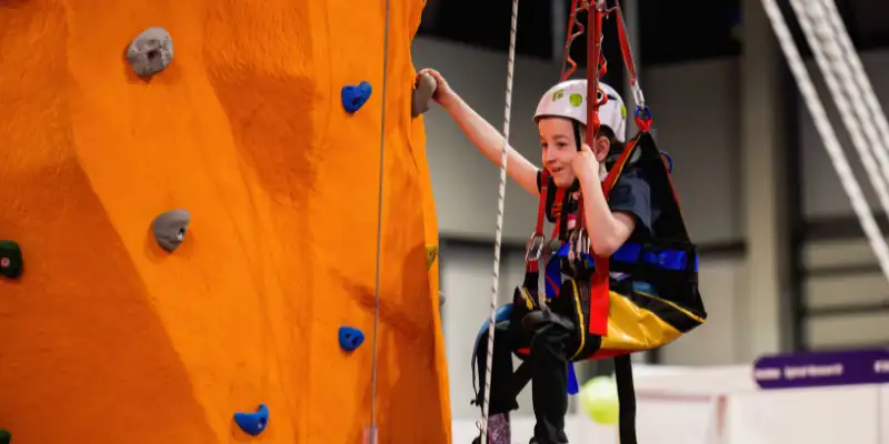 A close up picture of a child using the adaptive climbing wall, they are smiling.