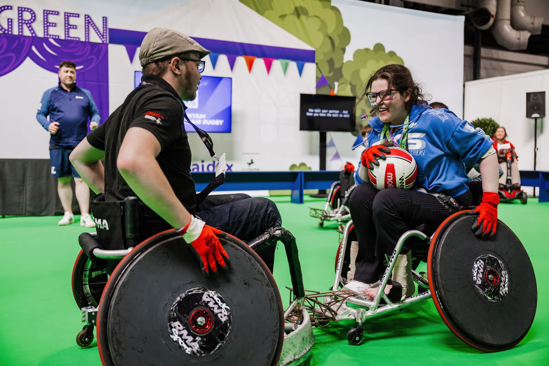 Visitors taking part in an inclusive wheelchair sports activity at Naidex, surrounded by colourful bunting and a lively crowd.