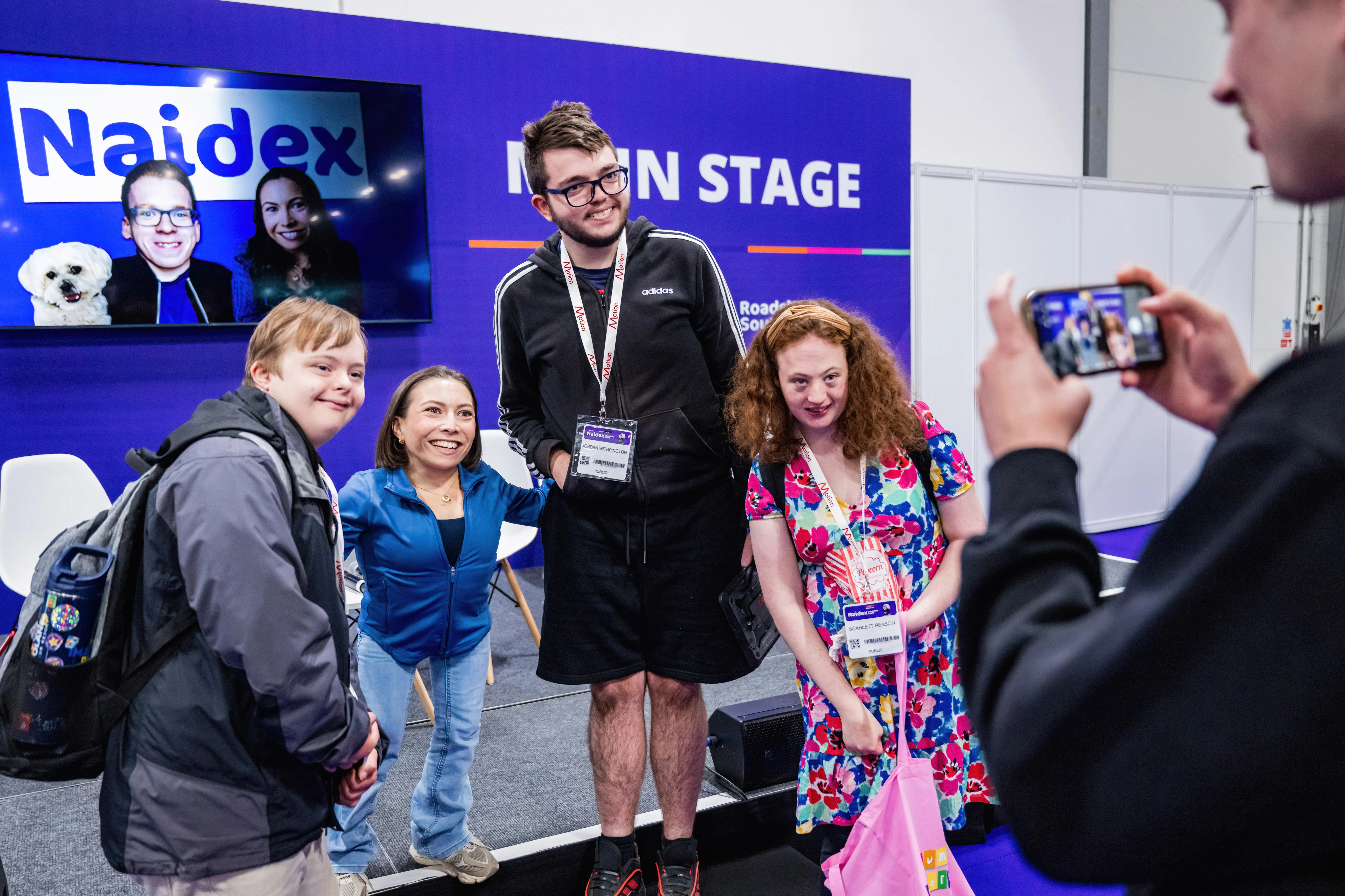Visitors taking part in an inclusive wheelchair sports activity at Naidex, surrounded by colourful bunting and a lively crowd.