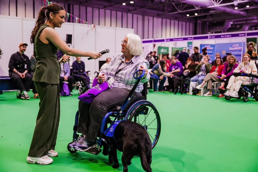 Visitors taking part in an inclusive wheelchair sports activity at Naidex, surrounded by colourful bunting and a lively crowd.