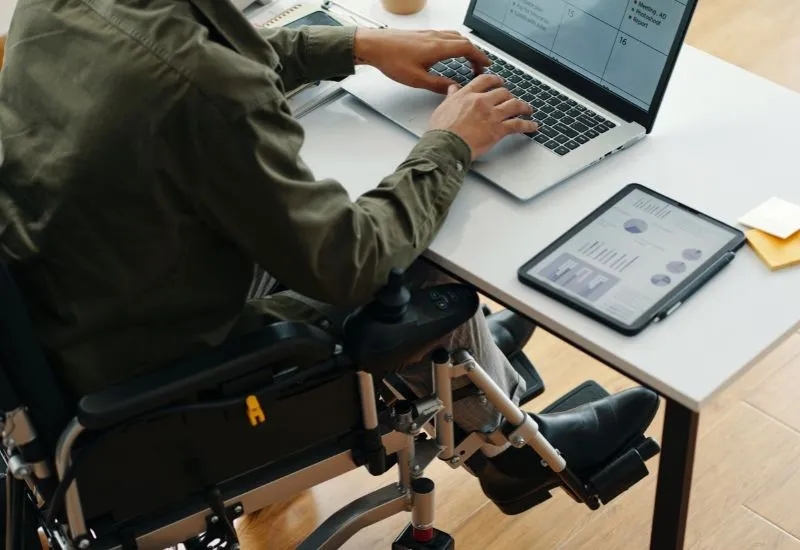 A disabled person at a desk typing on a computer