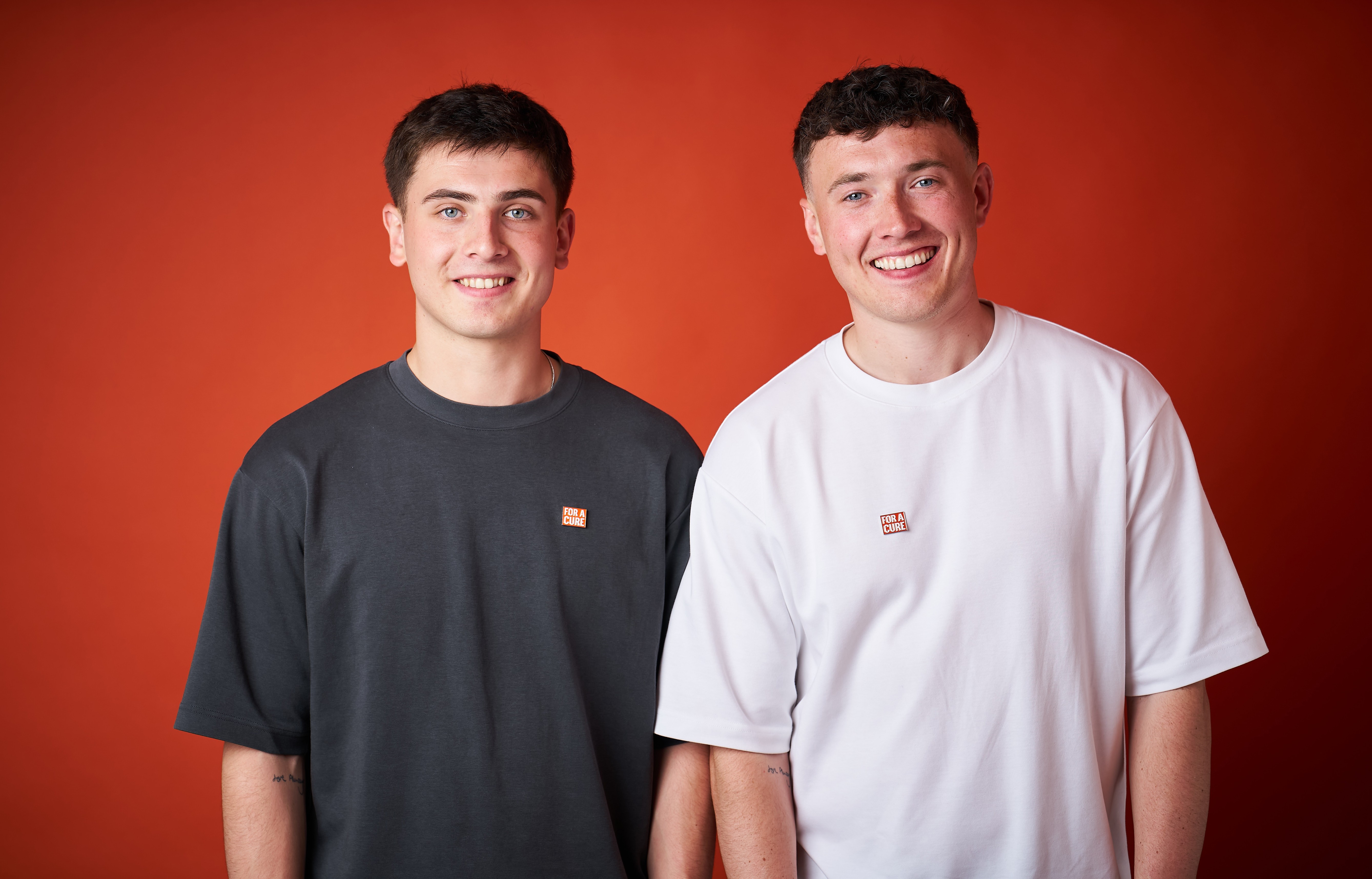 A picture of the two FDT Brothers smiling to the camera with a plain orange back ground