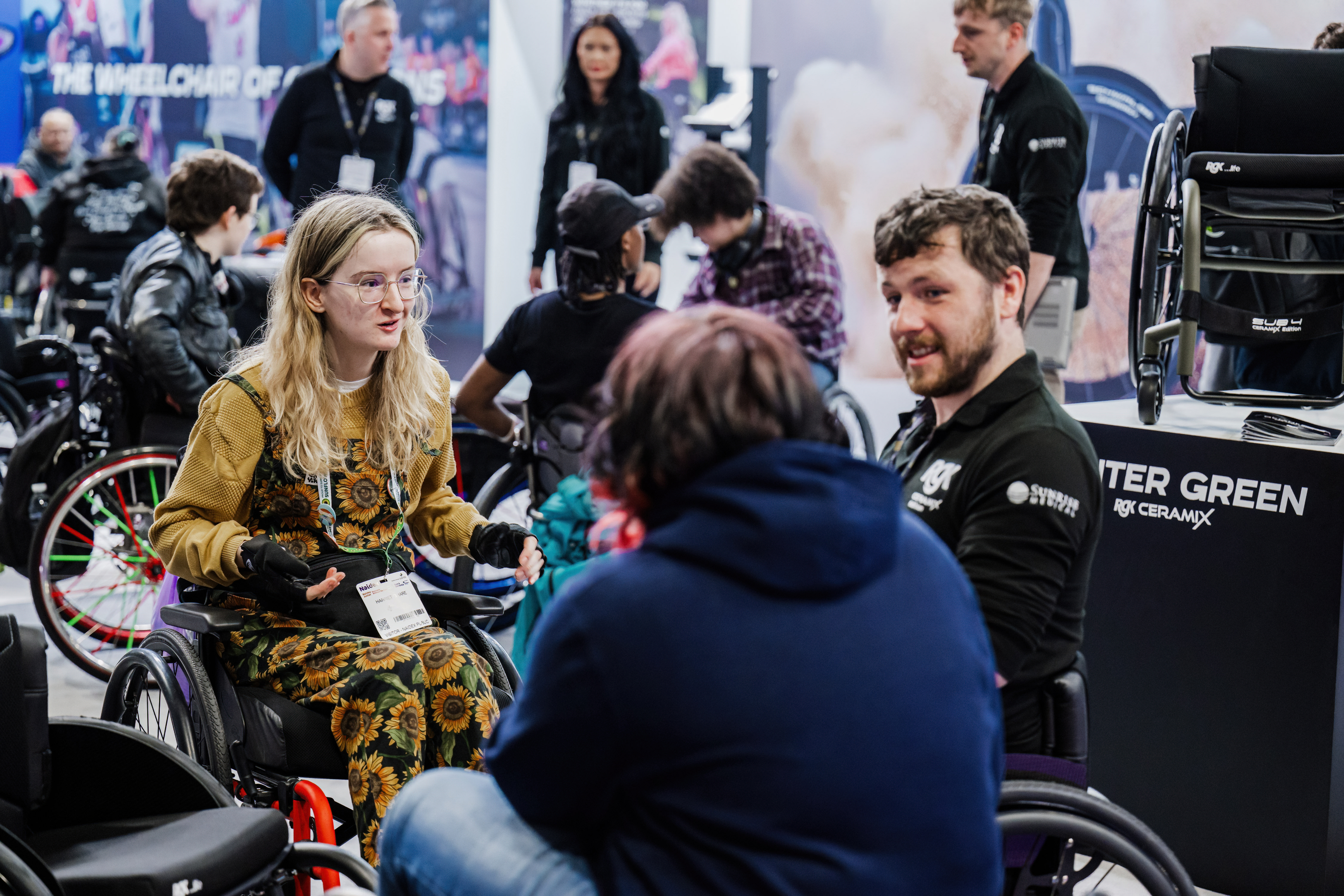 A picture of three people talking at Naidex 2026 at an exhibitor stand 