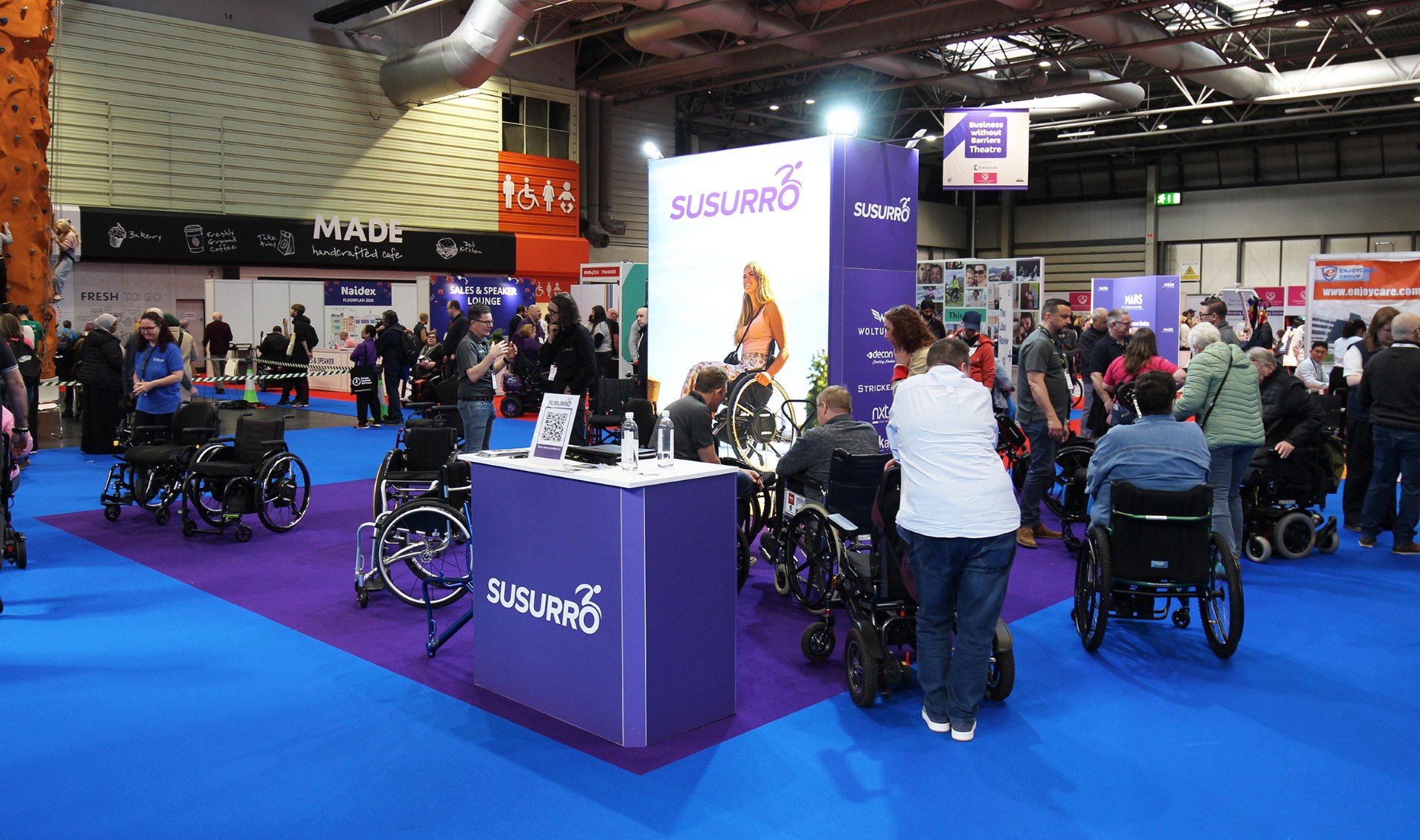 A picture of Ssuro's exhibition stand at Naidex 2025, there are lots of people who are gathered around the stand at the event 