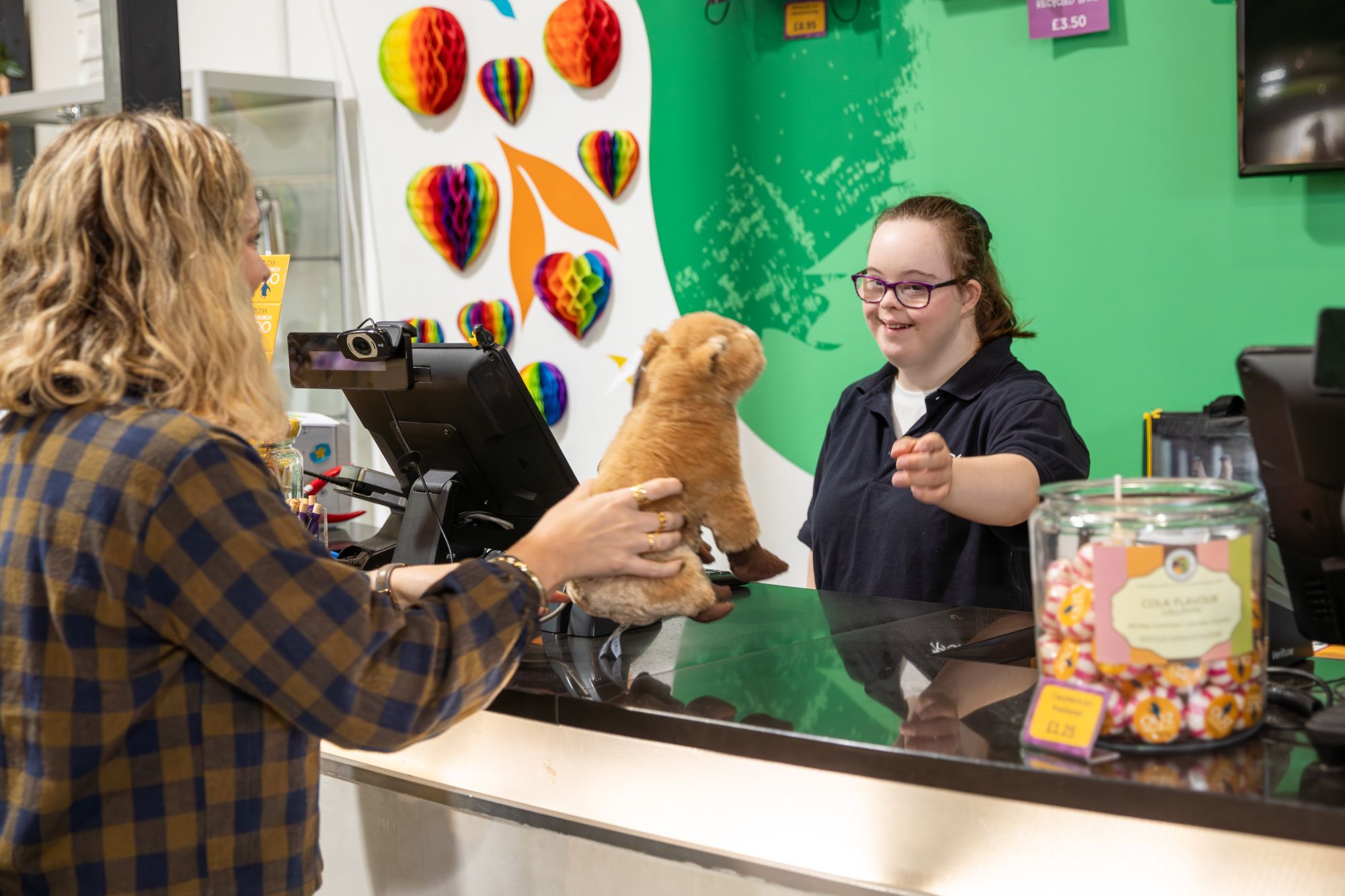 An image of a woman handing an employee a animal toy over a counter